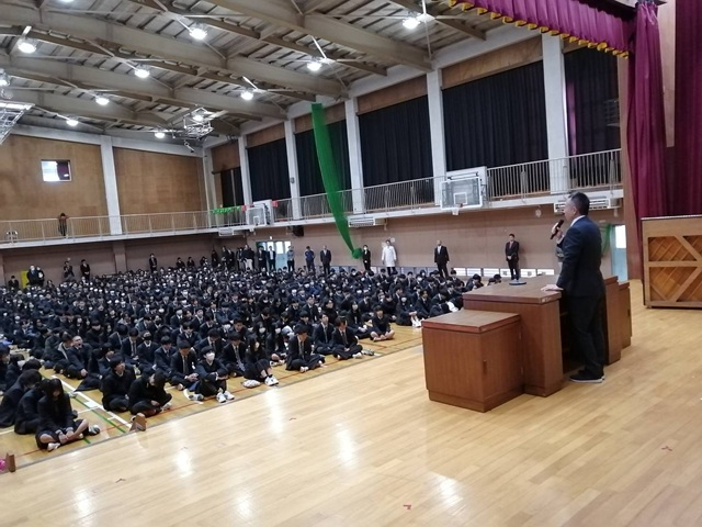 演台で話す教務部主任とそれを見つめる生徒