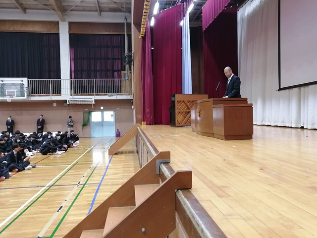 演台で話す生活指導部主任とそれを見つめる生徒