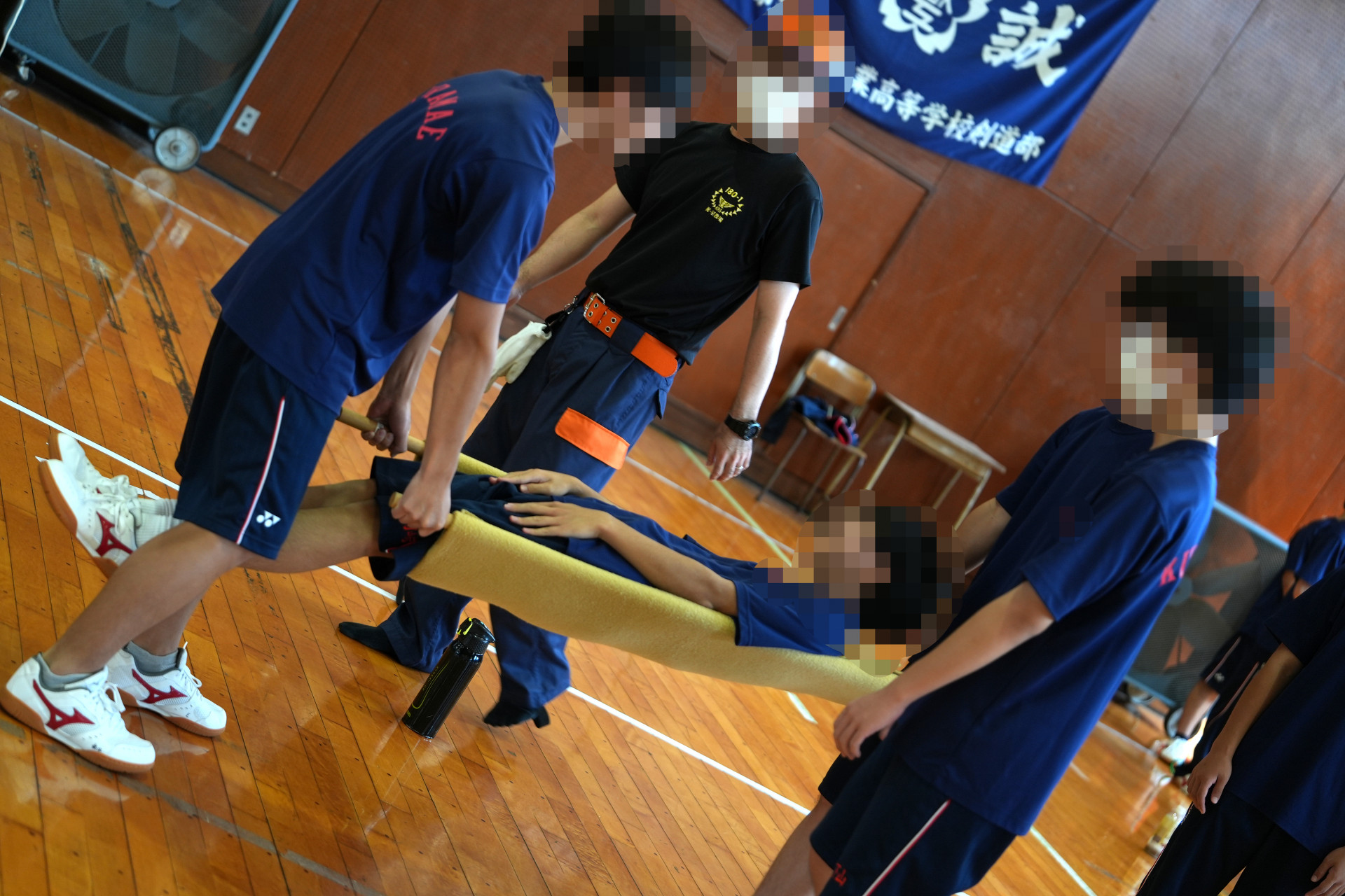 簡易担架でクラスメイトを運んでいる様子
